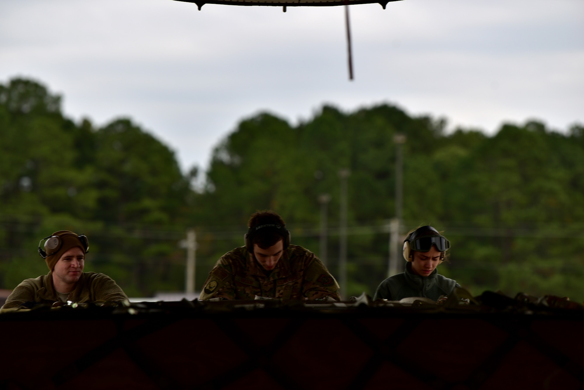 Personnel in uniform operate in and around an aircraft on an airfield