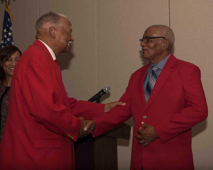 Dr. Harry Quinton, Documented Original Tuskegee Airmen (DOTA), congratulates U.S. Army Air Forces Sgt. Thomas Newton on receiving his red jacket and becoming a DOTA during a recognition ceremony in Hampton, Virginia, Nov. 13, 2019. Newton served with the 99th Fighter Squadron during World War II. (U.S. Air Force photo by Airman 1st Class Marcus M. Bullock)