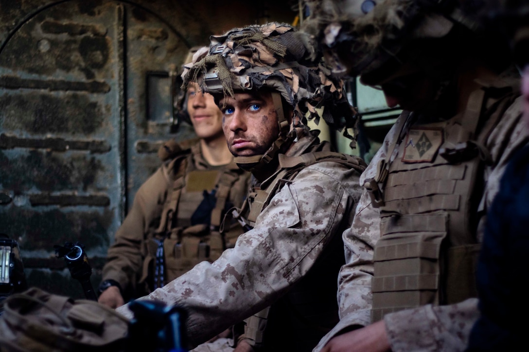 A Marine sitting down in between two other Marines.