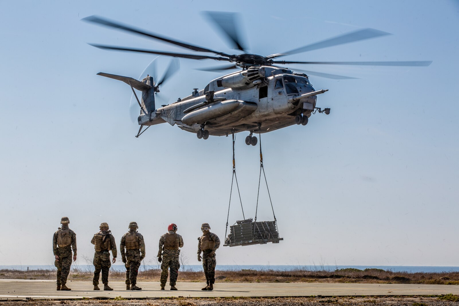U.S. Marines with Landing Support Company, 1st Transportation Battalion, prepare to detach pallets off a helicopter.