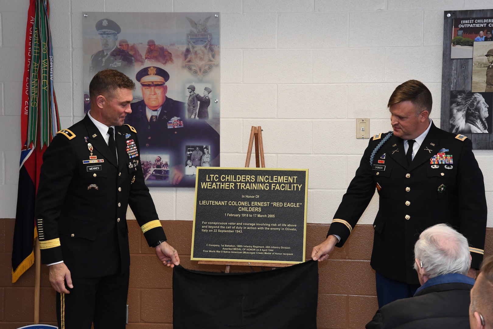 Maj. Gen. Brian J. Mennes, 10th Mountain Division (LI) and Fort Drum commander, and Col. Christopher Chomosh, representing the Oklahoma Army National Guard and 45th Infantry Division, unveil a plaque honoring retired Lt. Col. Ernest Childers Nov. 20, 2019, at Fort Drum. The LTC Childers Inclement Weather Training Facility honors the first American Indian Medal of Honor recipient of the 20th century.