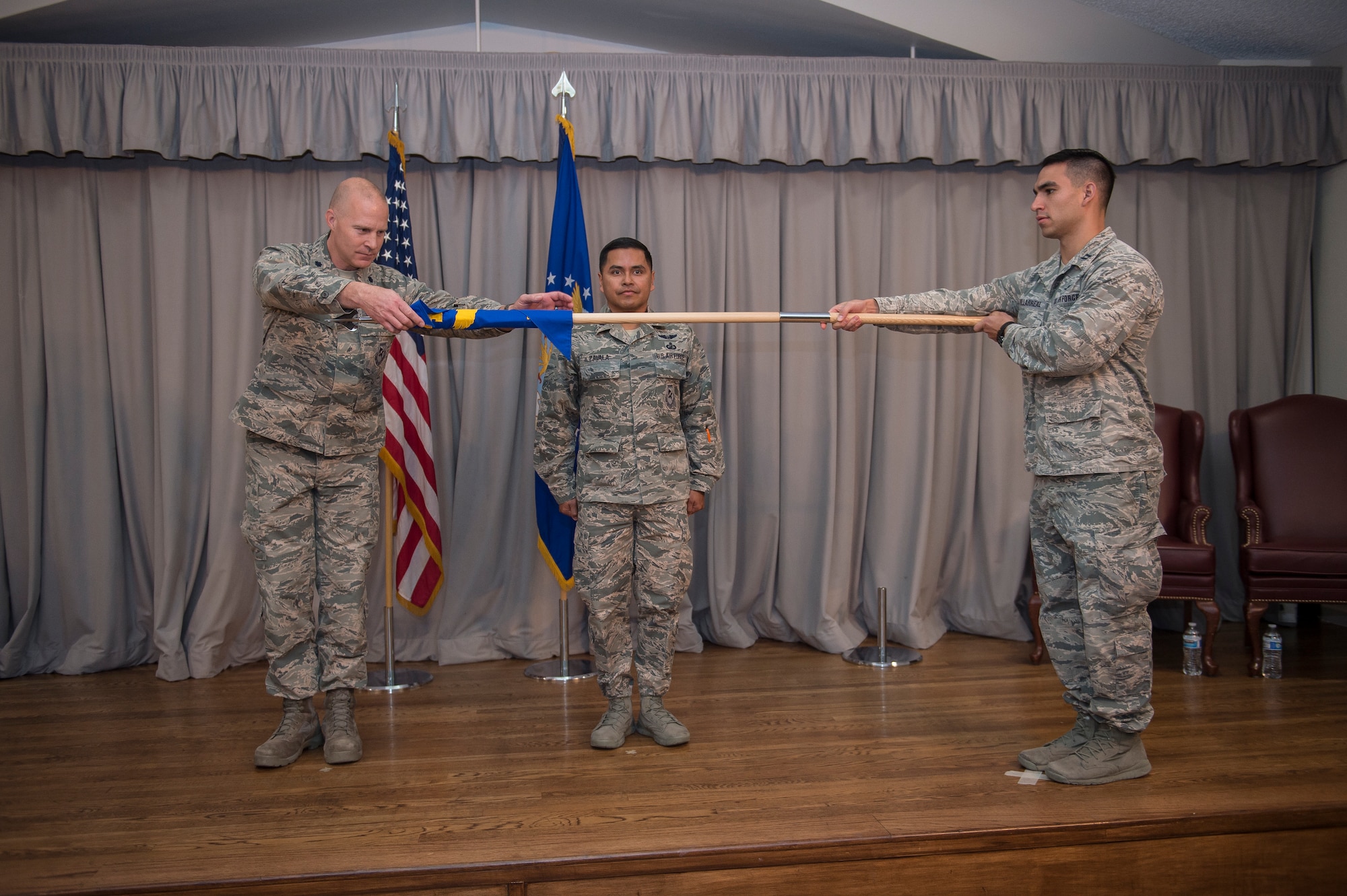 Lt. Col. Corey Beaverson, 47th Cyberspace Test Squadron Commander, unfurls the unit guidon for Detachment 1, 47th CTS, during the detachment's activation ceremony at Edwards Air Force Base, California, Nov. 19. Det. 1 will be commanded by Lt. Col. Ever Zavala (center). (Air Force photo by Joshua Miller)
