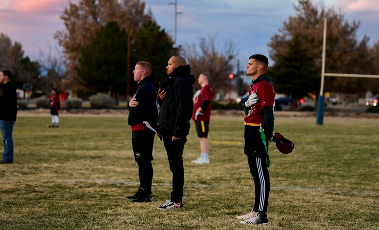 A photo football players standing with their hands over their hearts.