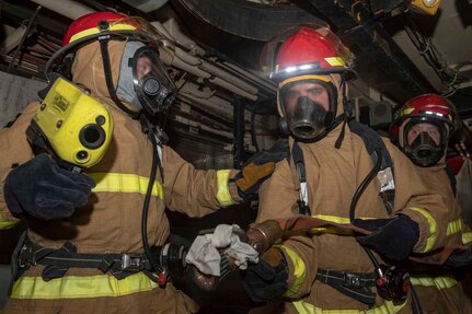 Navy firefighters check a cabin.