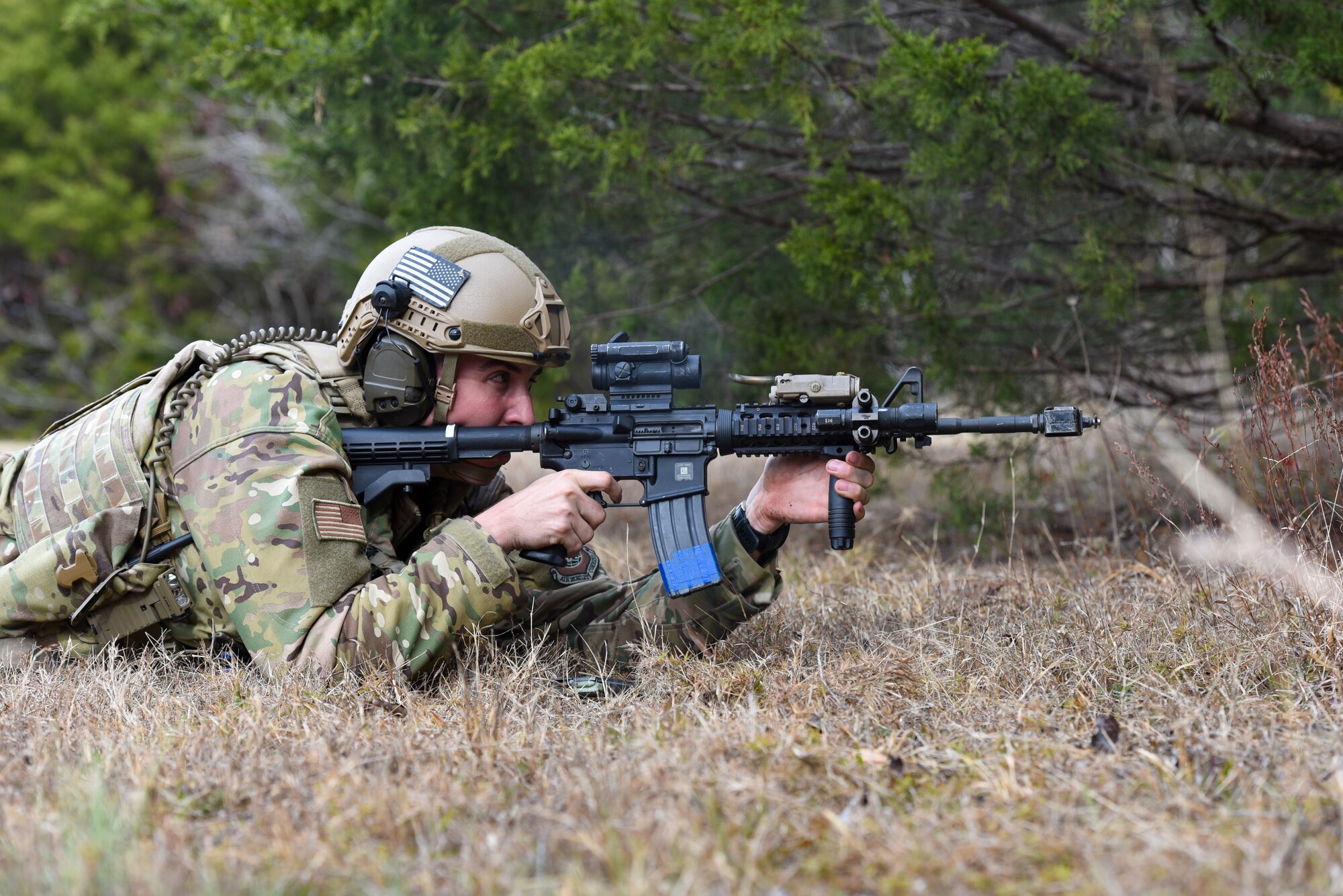An Airman lays in the prone position with an M4 rifle