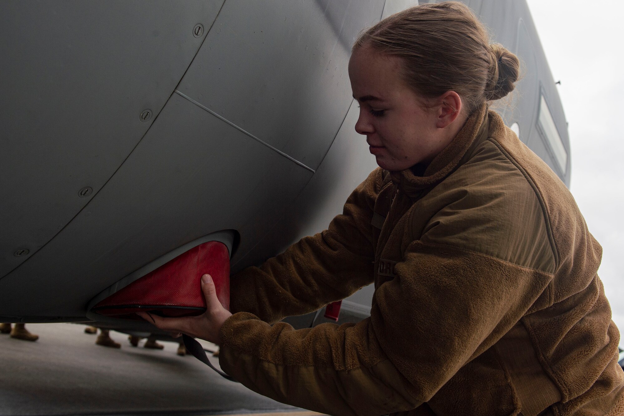 A photo of an Airman installing a plug onto the outside of an aircraft.