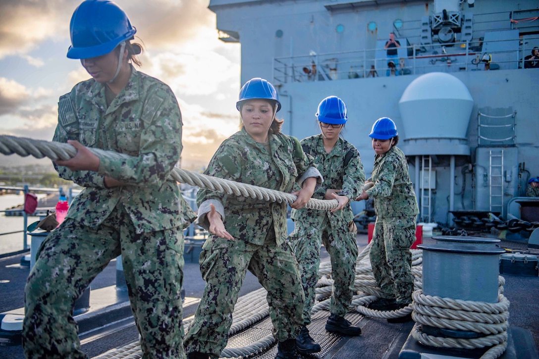 Four sailors pull on a rope.