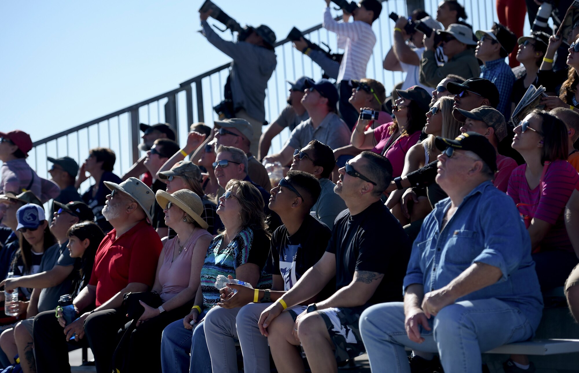 Aviation Nation attendees look to the sky as the MQ-9 Reaper flies by, at Nellis Air Force Base, Nevada, Nov. 16, 2019. Even though the MQ-9 Reaper static display is normally available at Nellis’ Aviation Nation, this is the first time an MQ-9 has performed a flyover. (U.S. Air Force photo by Airman 1st Class William Rio Rosado)