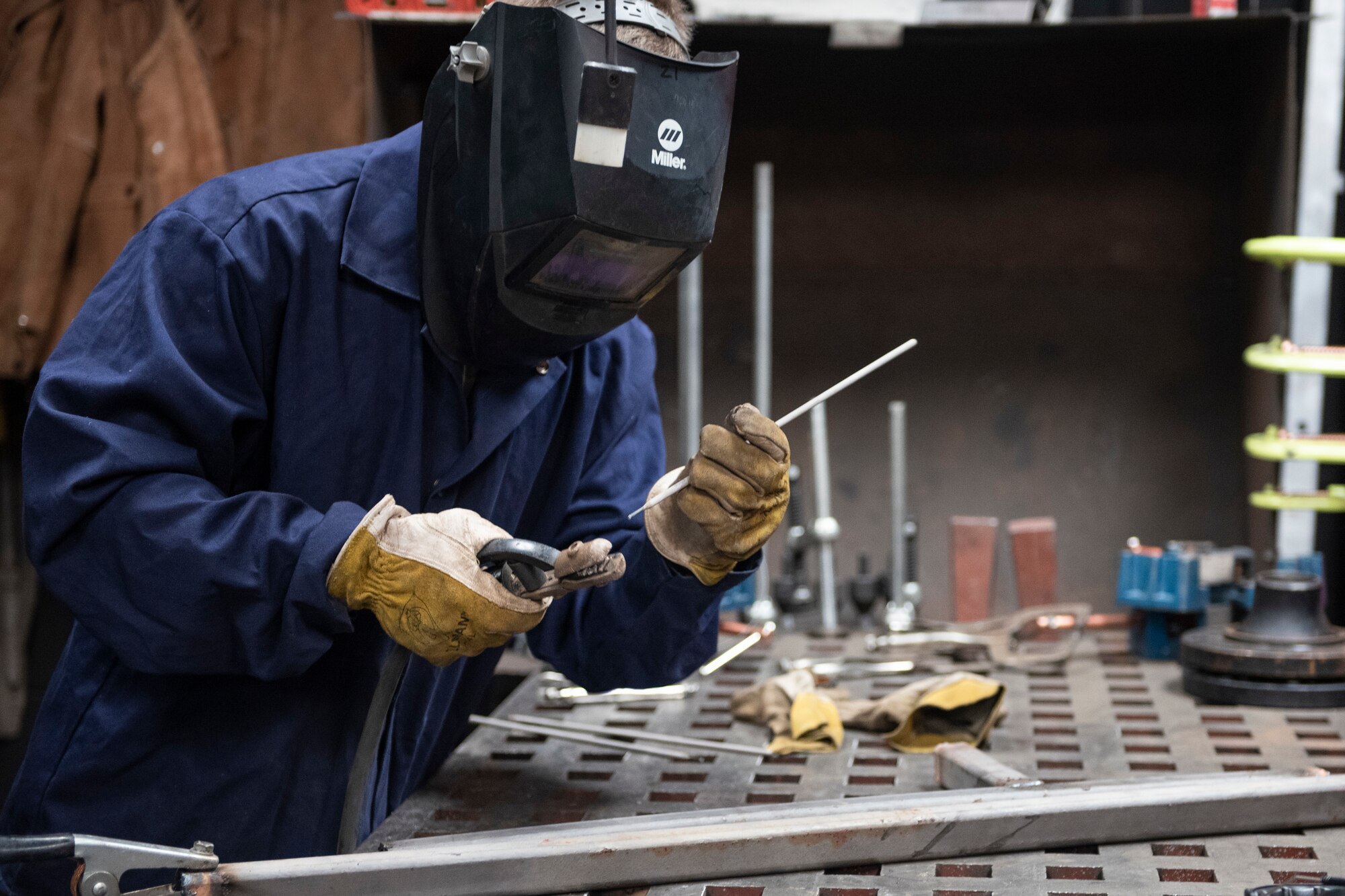 A photo of an Airman attaching an electrode to an arc welding electrode holder