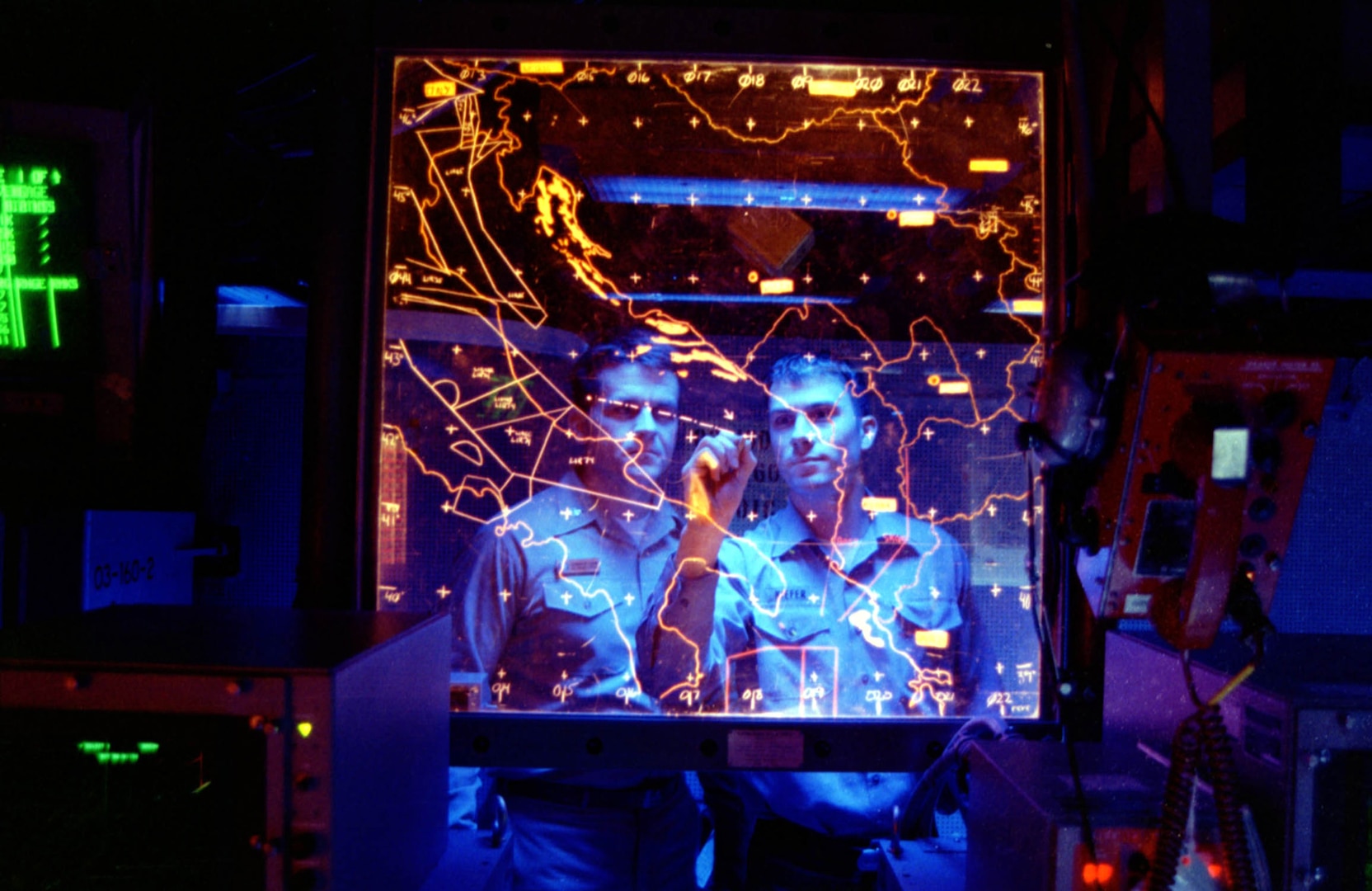 Sailors review manual tracking procedures of target using plot board in Combat Direction Center at sea aboard USS Theodore Roosevelt in support of Allied Force, Adriatic Sea, June 3, 1999 (U.S. Navy/William L. Vandermate)