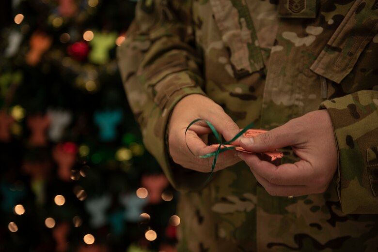 A photo of an Airman holding tree ornament during a holiday event.