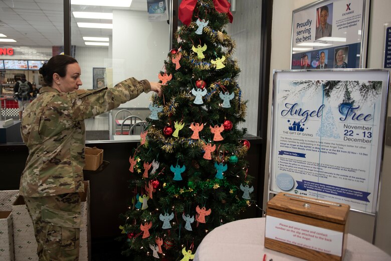 A photo of an Airman hanging an ornament on a tree.