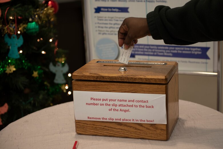 A photo of a person placing a donation idea into a box.
