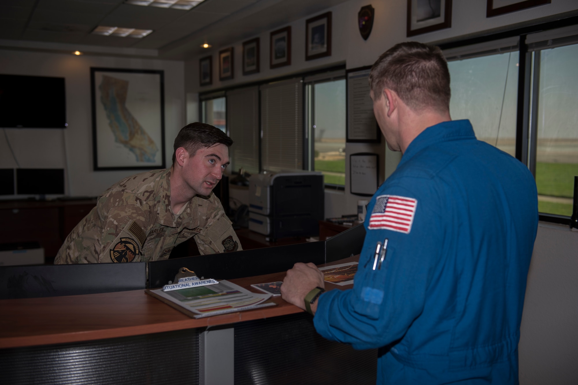 U.S. Air Force Senior Airman Dylan Marler, 60th Operation Support Squadron weather forecaster, speaks with Donald Darrow, NASA special equipment operator Nov. 18, 2019, at Travis Air Force Base California. Marler informs NASA personnel about the local weather so they know if they can proceed with their work. (U.S. Air Force photo by Airman 1st Class Cameron Otte)