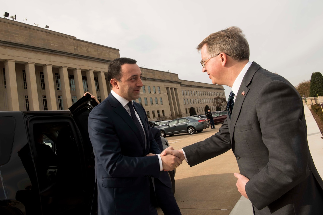 Two men shake hands.