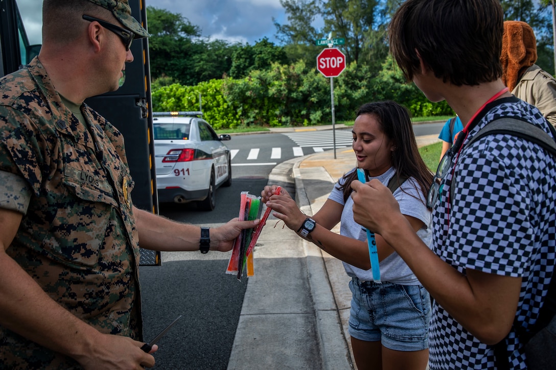 U.S. Marine Corps Gunnery Sgt. Mark Lyons, the training chief for the Provost Marshal's Office, Headquarters Battalion, Marine Corps Base Hawaii (MCBH), hands out Otter Pops to children, MCBH, Nov. 20, 2019. Members of the Provost Marshal's Office drove around the installation, handing out Otter Pops to children and parents while informing residents about upcoming events to get the community more involved. (U.S. Marine Corps photo by Cpl. Matthew Kirk)