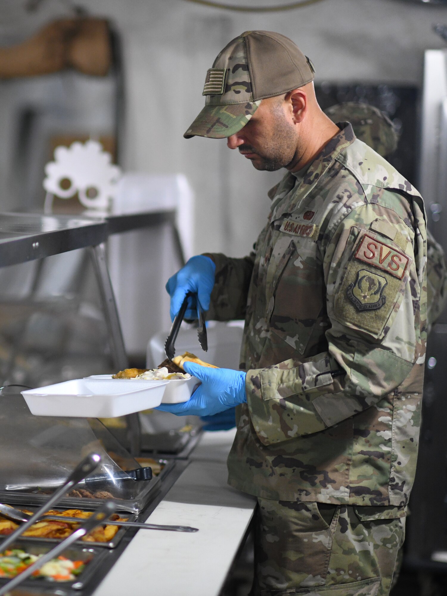 U.S. Air Force Staff Sgt. Carlos Ortega, 776th Expeditionary Air Base Squadron Services NCO in-charge of food and beverages, serves food to dining facility patrons at Chabelley Airfield, Djibouti, Nov. 13, 2109. The services Airmen receive, inspect, prepare and serve roughly 800 meals each day to Airmen, Soldiers and contractors fulfilling their duties on the airfield. (U.S. Air Force photo by Staff Sgt. Alex Fox Echols III)