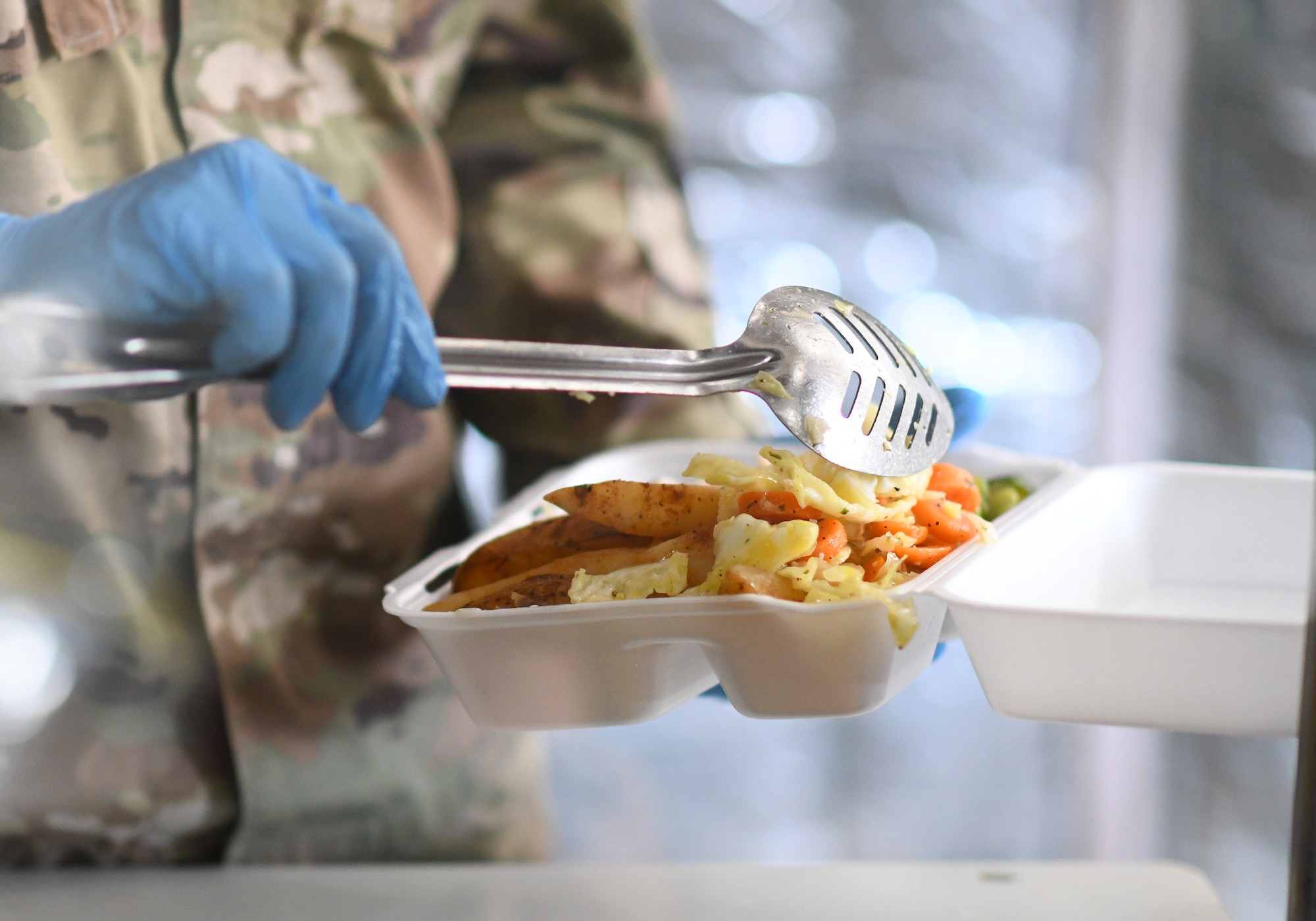 A member of the 776th Expeditionary Air Base Squadron Services team serves food to dining facility patrons at Chabelley Airfield, Djibouti, Nov. 13, 2109. The services Airmen receive, inspect, prepare and serve roughly 800 meals each day to Airmen, Soldiers and contractors fulfilling their duties on the airfield. (U.S. Air Force photo by Staff Sgt. Alex Fox Echols III)