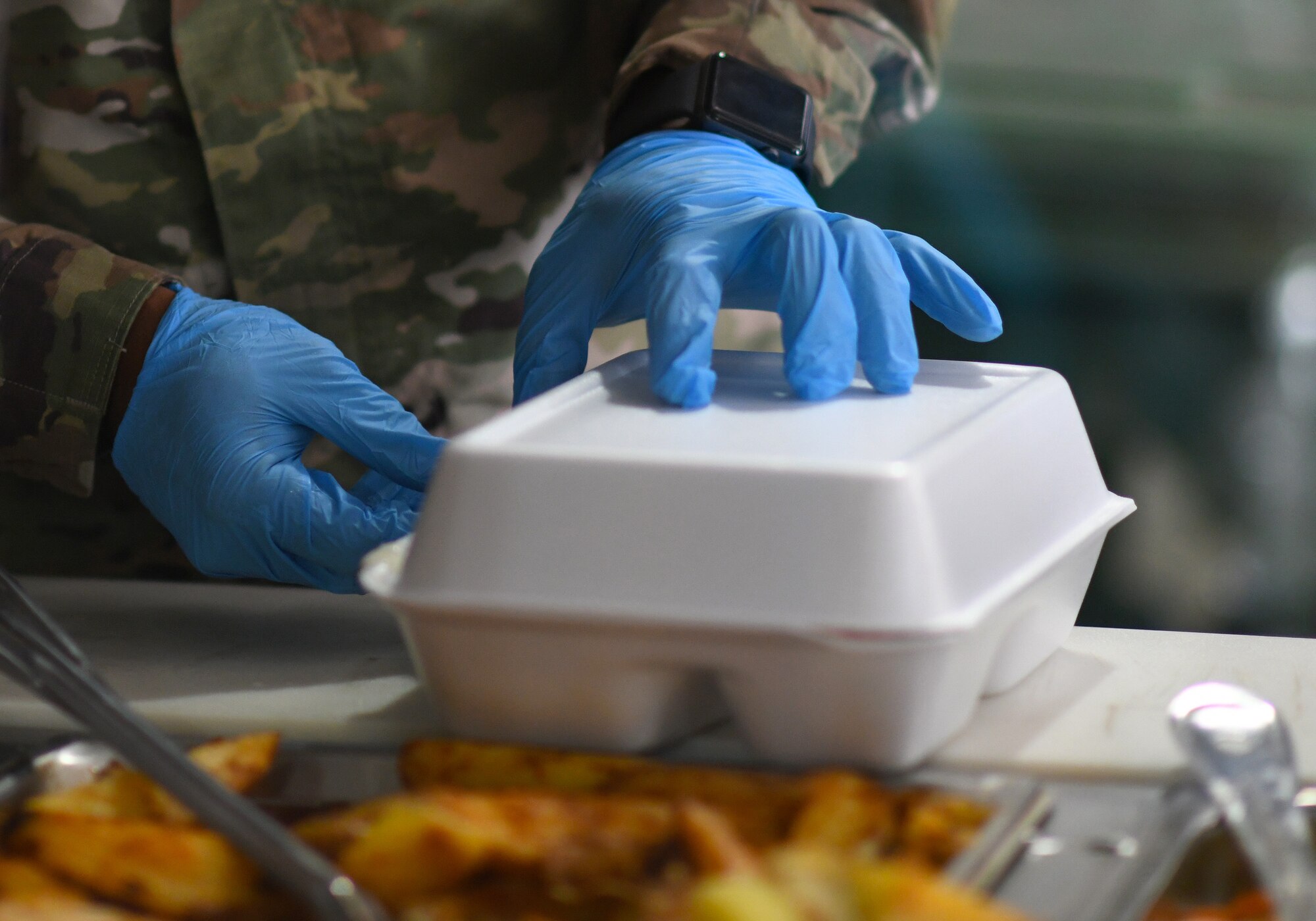 A member of the 776th Expeditionary Air Base Squadron Services team serves food to dining facility patrons at Chabelley Airfield, Djibouti, Nov. 13, 2109. The services Airmen receive, inspect, prepare and serve roughly 800 meals each day to Airmen, Soldiers and contractors fulfilling their duties on the airfield. (U.S. Air Force photo by Staff Sgt. Alex Fox Echols III)