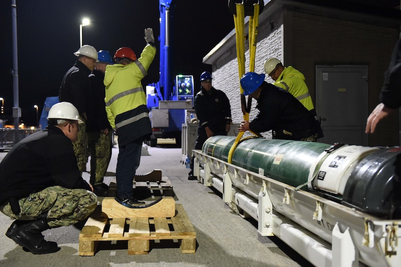 Sailors move a torpedo.