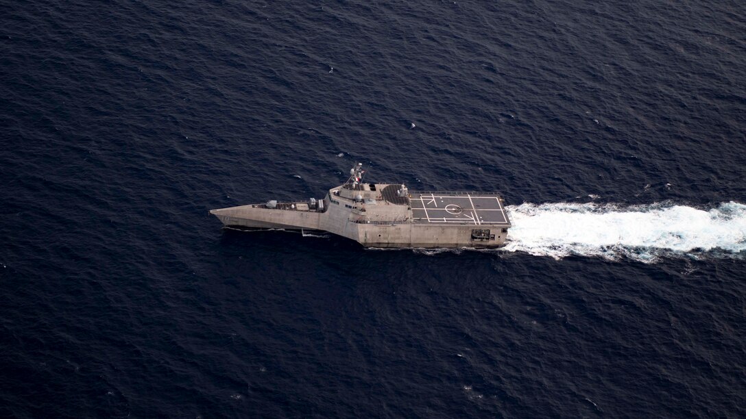 A littoral combat ship sails in the sea leaving a white wake behind.
