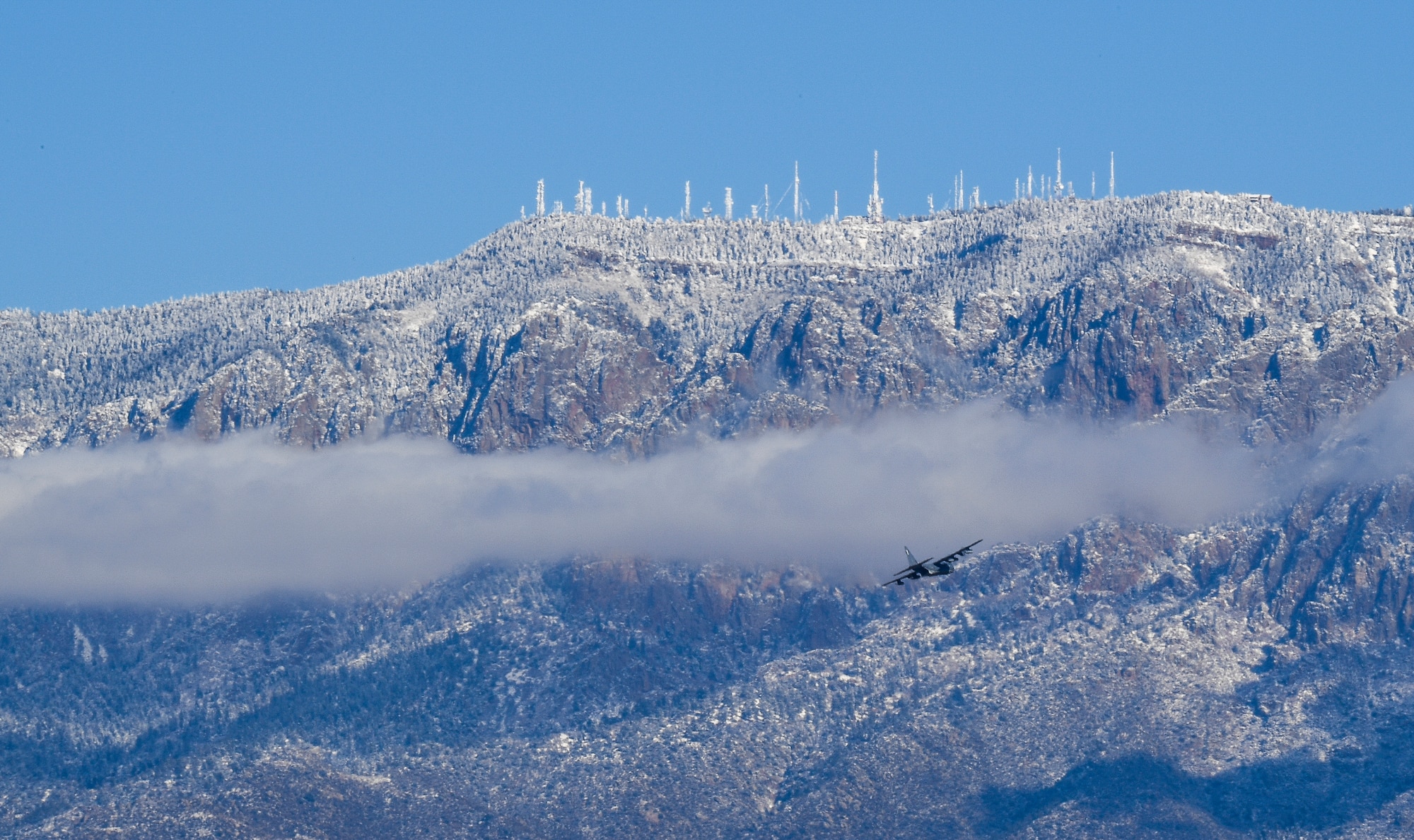Photo of aircraft flying near mountains.