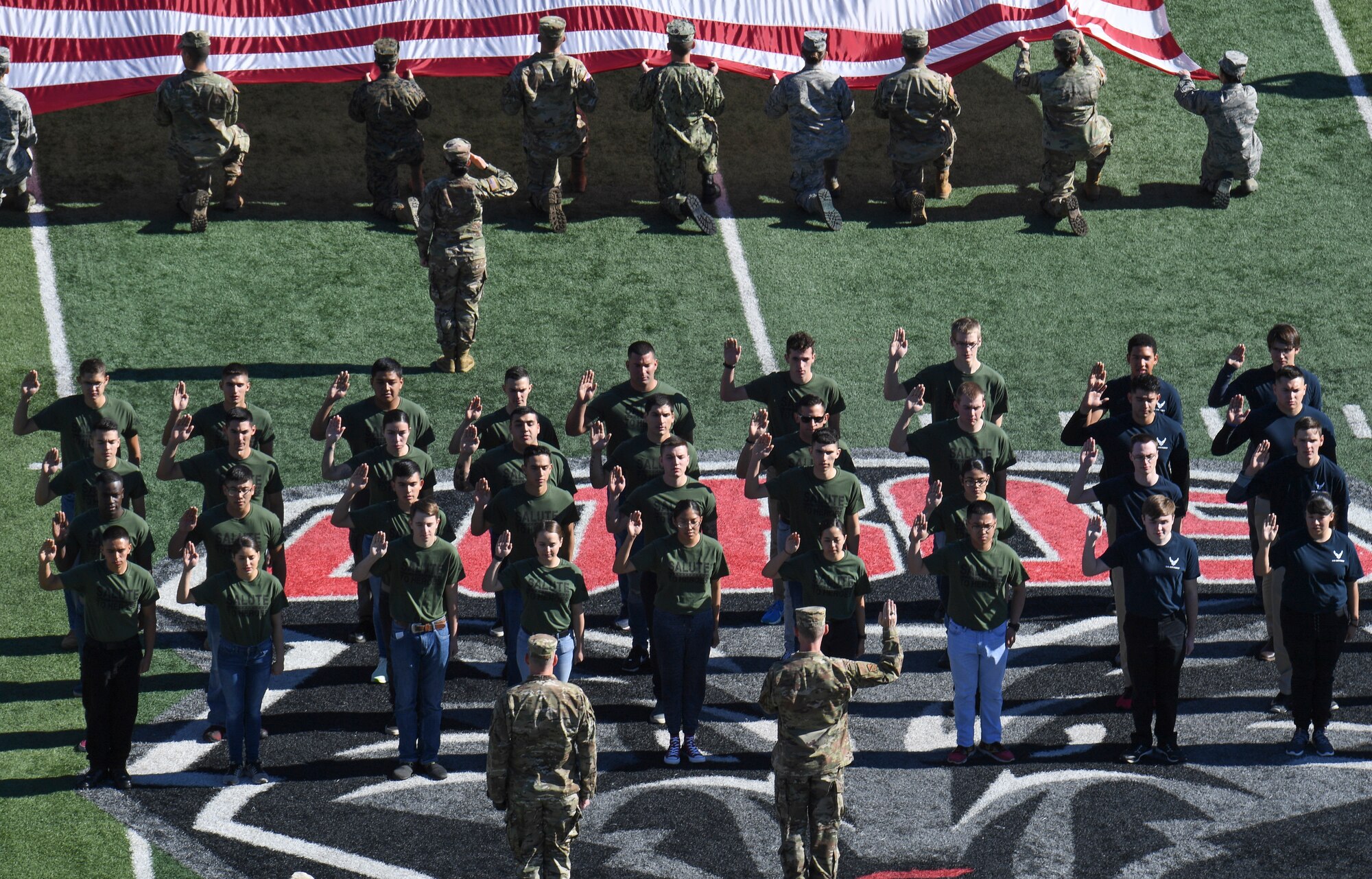Photo of future service members getting sworn in on football field.