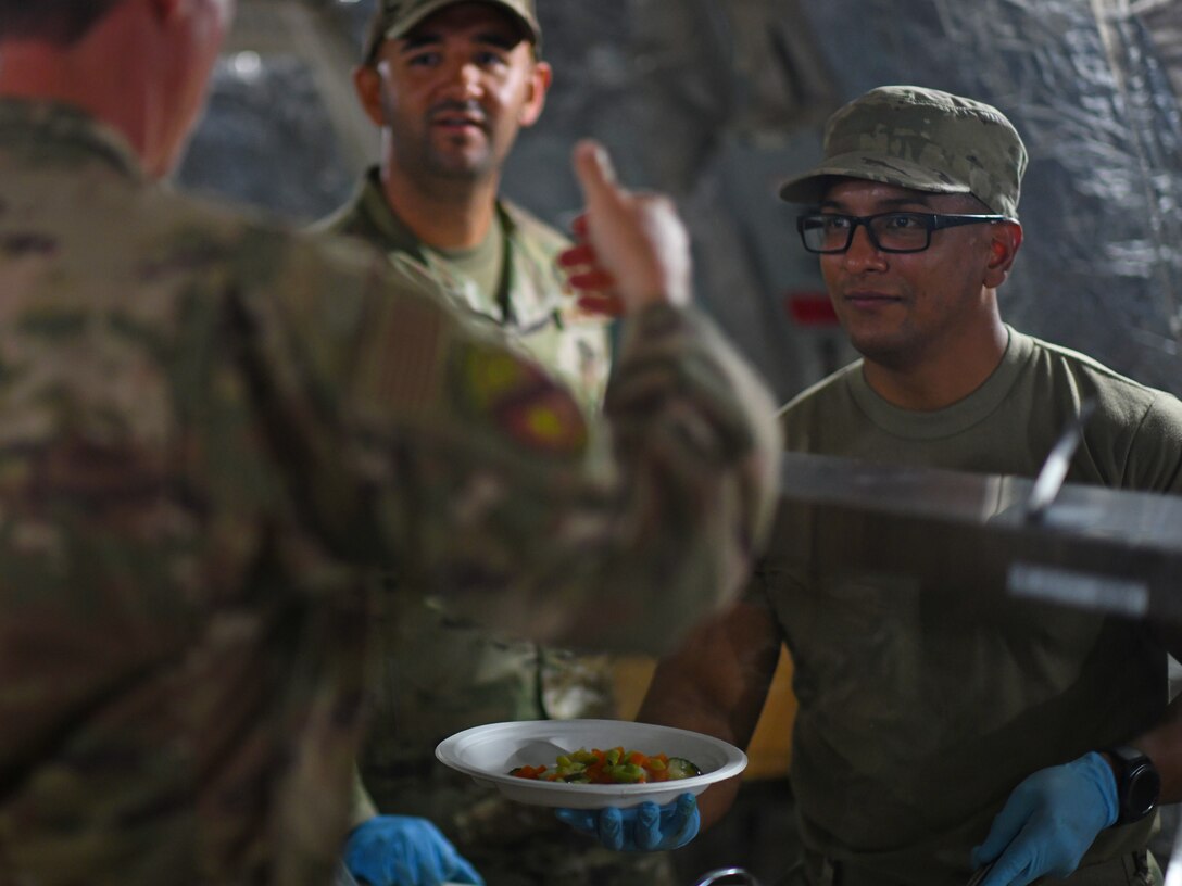 U.S. Air Force Staff Sgt. Carlos Ortega, left, and Tech. Sgt. Juan Serrano, 776th Expeditionary Air Base Squadron Services food and beverage NCO in-charge and assistant manager, serve food to dining facility patrons at Chabelley Airfield, Djibouti, Nov. 13, 2109. Like most of the 776th EABS services team, Ortega and Serrano are deployed from the 156th Wing, Puerto Rico Air National Guard at Muñiz Air National Guard Base, Carolina, Puerto Rico. (U.S. Air Force photo by Staff Sgt. Alex Fox Echols III)