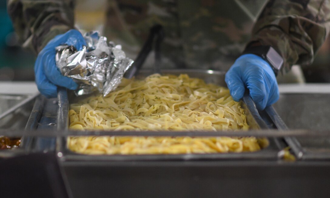 A member of the 776th Expeditionary Air Base Squadron Services team adds pasta to the serving line at the dining facility on Chabelley Airfield, Djibouti, Nov. 13, 2109. The services Airmen receive, inspect, prepare and serve roughly 800 meals each day to Airmen, Soldiers and contractors fulfilling their duties on the airfield. (U.S. Air Force photo by Staff Sgt. Alex Fox Echols III)