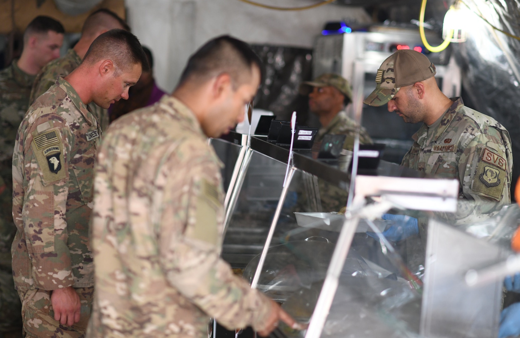 Members of the 776th Expeditionary Air Base Squadron Services team serve food to dining facility patrons at Chabelley Airfield, Djibouti, Nov. 13, 2109. The services Airmen receive, inspect, prepare and serve roughly 800 meals each day to Airmen, Soldiers and contractors fulfilling their duties on the airfield. (U.S. Air Force photo by Staff Sgt. Alex Fox Echols III)