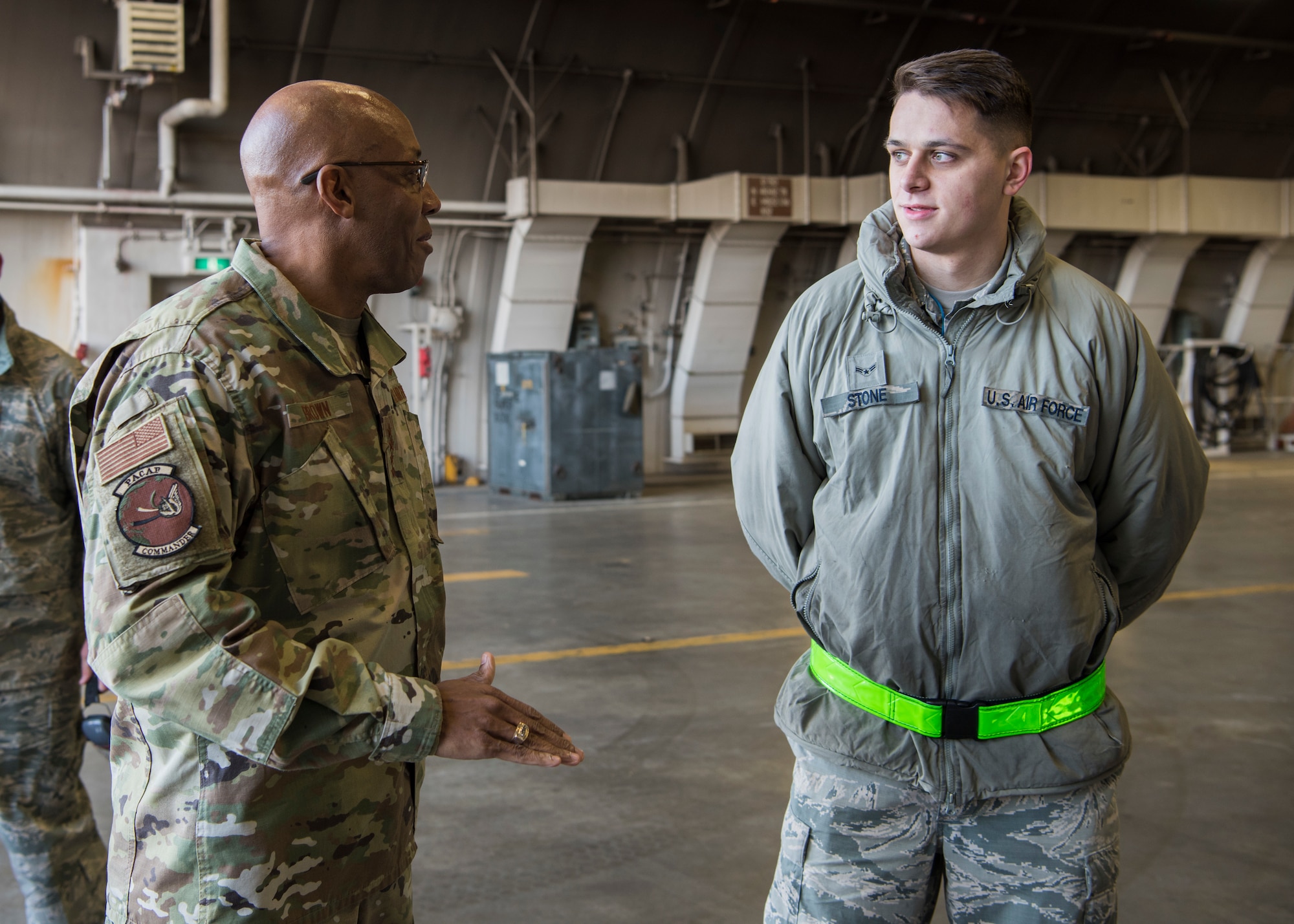 U.S. Air Force Gen. CQ Brown Jr., Pacific Air Forces commander, speaks with Airman 1st Class Daniel Stone, 35th Maintenance Group weapons load crew member, prior to coining him at Misawa Air Base, Japan, Nov. 14, 2019. During his visit Brown coined various Airmen who their leadership described as exceptional work performers, resilient and a major asset to the units’ morale and workforce. (U.S. Air Force Photo by Senior Airman Collette Brooks)