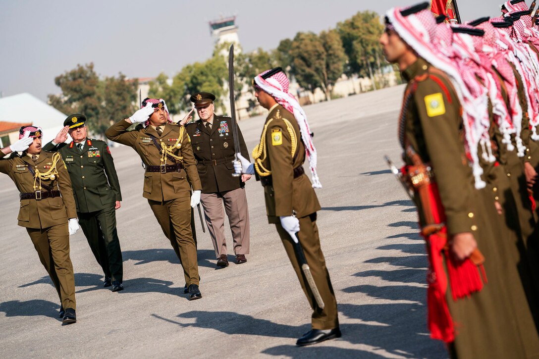 U.S. and foreign military leaders salute a formation.