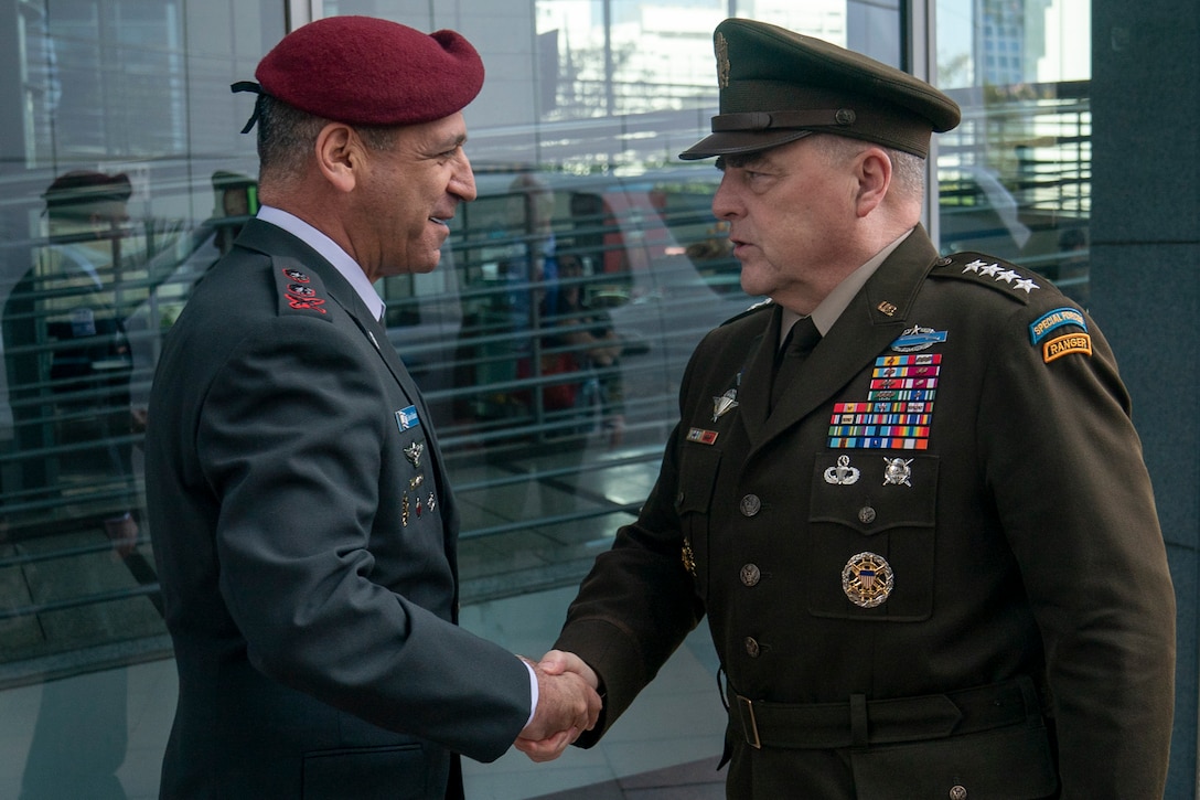 Two men in service uniforms shake hands.