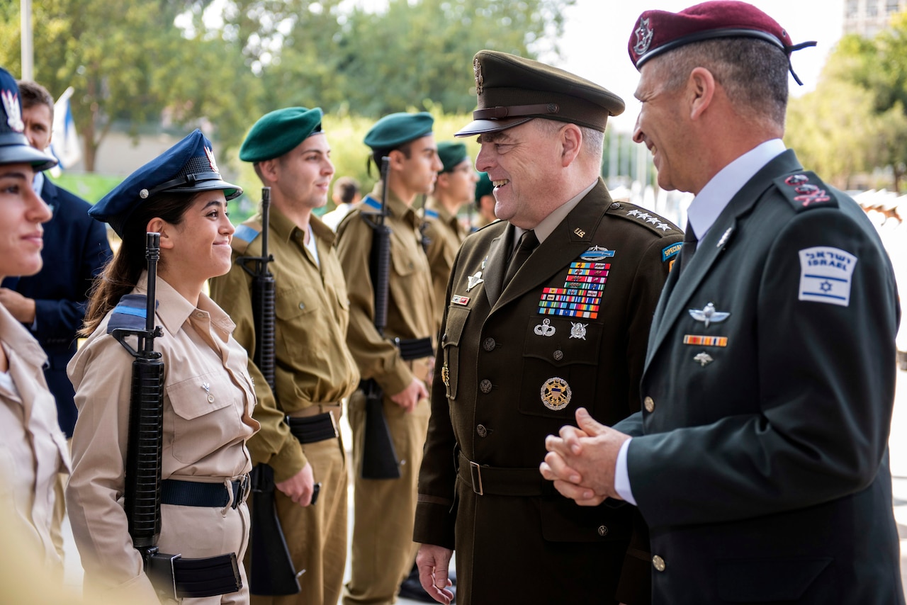 Two uniformed officers speak with service members standing in a line.