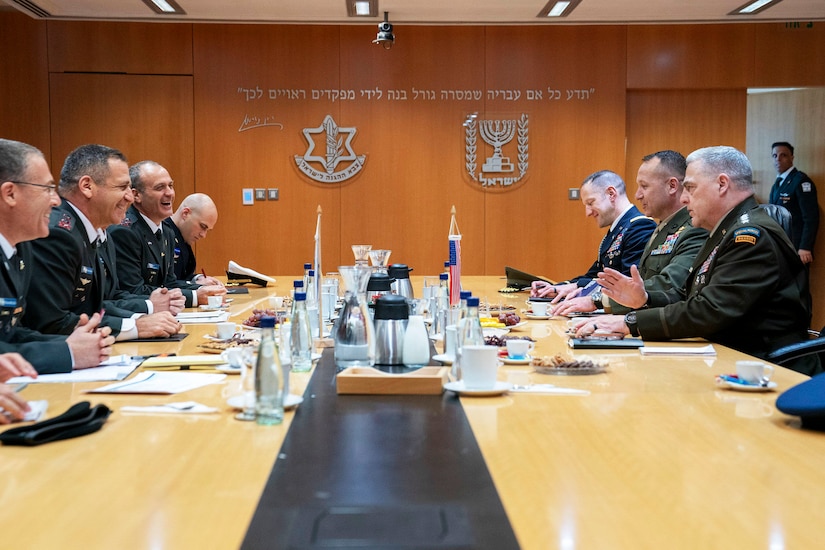 A group of military officers sit around a large table.