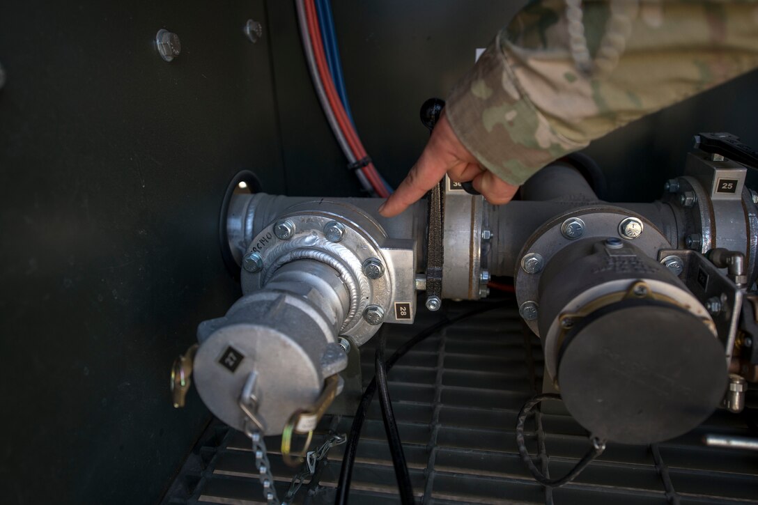 Tech. Sgt. Thomas Harris, 49th Logistics Readiness Squadron non-commissioned officer in charge of fuels distribution, points out a retrofitted adapter, Nov. 14, 2019, on Holloman Air Force Base, N.M. Airmen from the fuels distribution element developed an idea to increase fuels support for ground vehicles and equipment. (U.S. Air Force photo by Staff Sgt. Christine Groening)