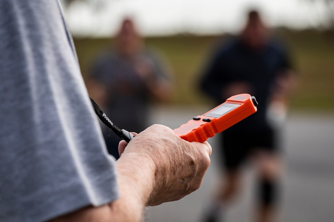 A photo of a health promotion coordinator recording run times during the Health and Readiness Optimization Dash 4K