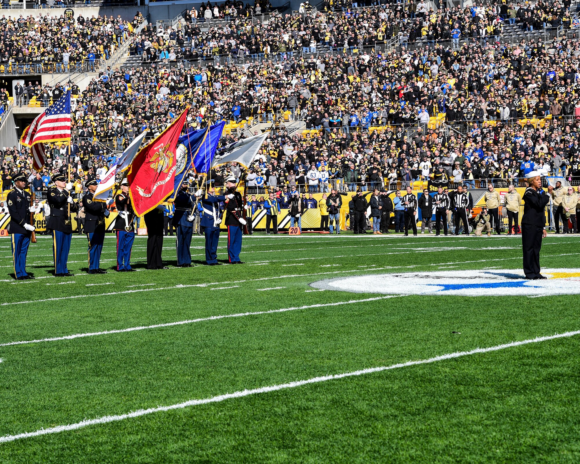 U.S. Navy Hospital Corpsman 1st Class Tanqueray Hayward performs the National Anthem with a color guard composed of members from all military branches at a Pittsburgh Steelers vs. Indianapolis Colts game at Heinz Field in Pittsburgh, Pennsylvania, November 3, 2019.