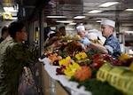 Capt. Colby Howard (right), commanding officer of the amphibious assault ship USS Wasp (LHD 1), serves a traditional Thanksgiving meal to sailors during a celebration aboard the ship forward deployed to Sasebo, Japan, Nov. 22, 2018. Each year, DLA Troop Support Subsistence supply chain employees ensure service members around the world get to enjoy a traditional Thanksgiving meal. (U.S. Navy photo by Mass Communication Specialist 1st Class Daniel Barker)