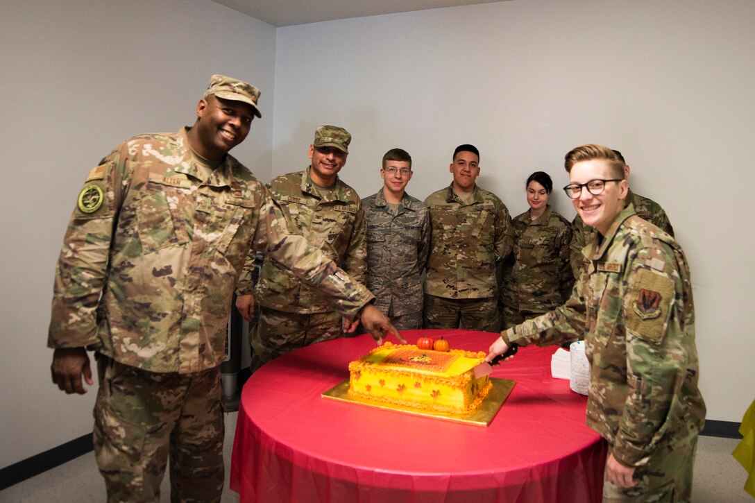 A photo of Airmen posing before cutting cake at the Annual Airman Thanksgiving Lunch