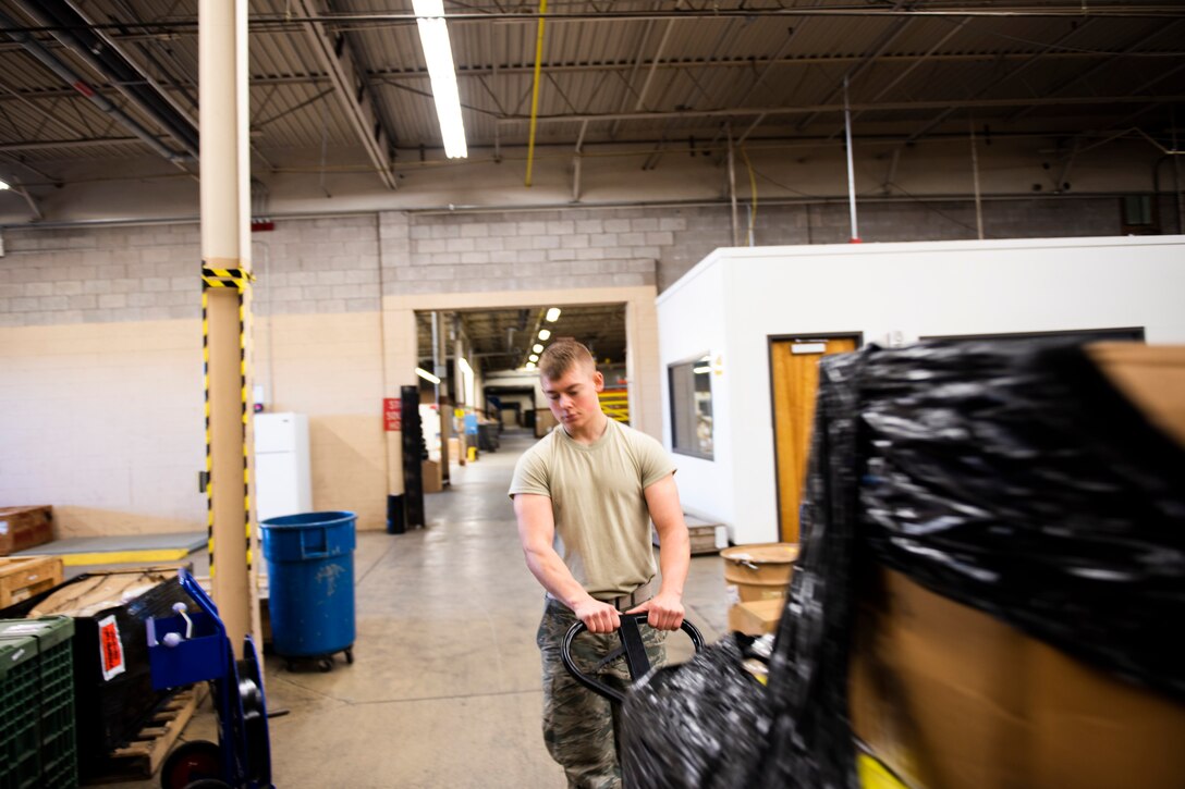 A photo of an Airman using a pallet jack to move heavy equipment.