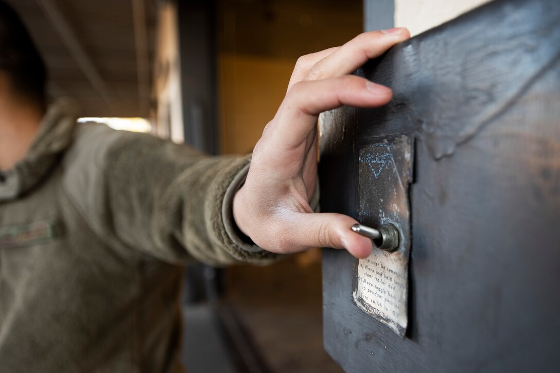 A photo of an Airman flipping a switch that controls a ramp.