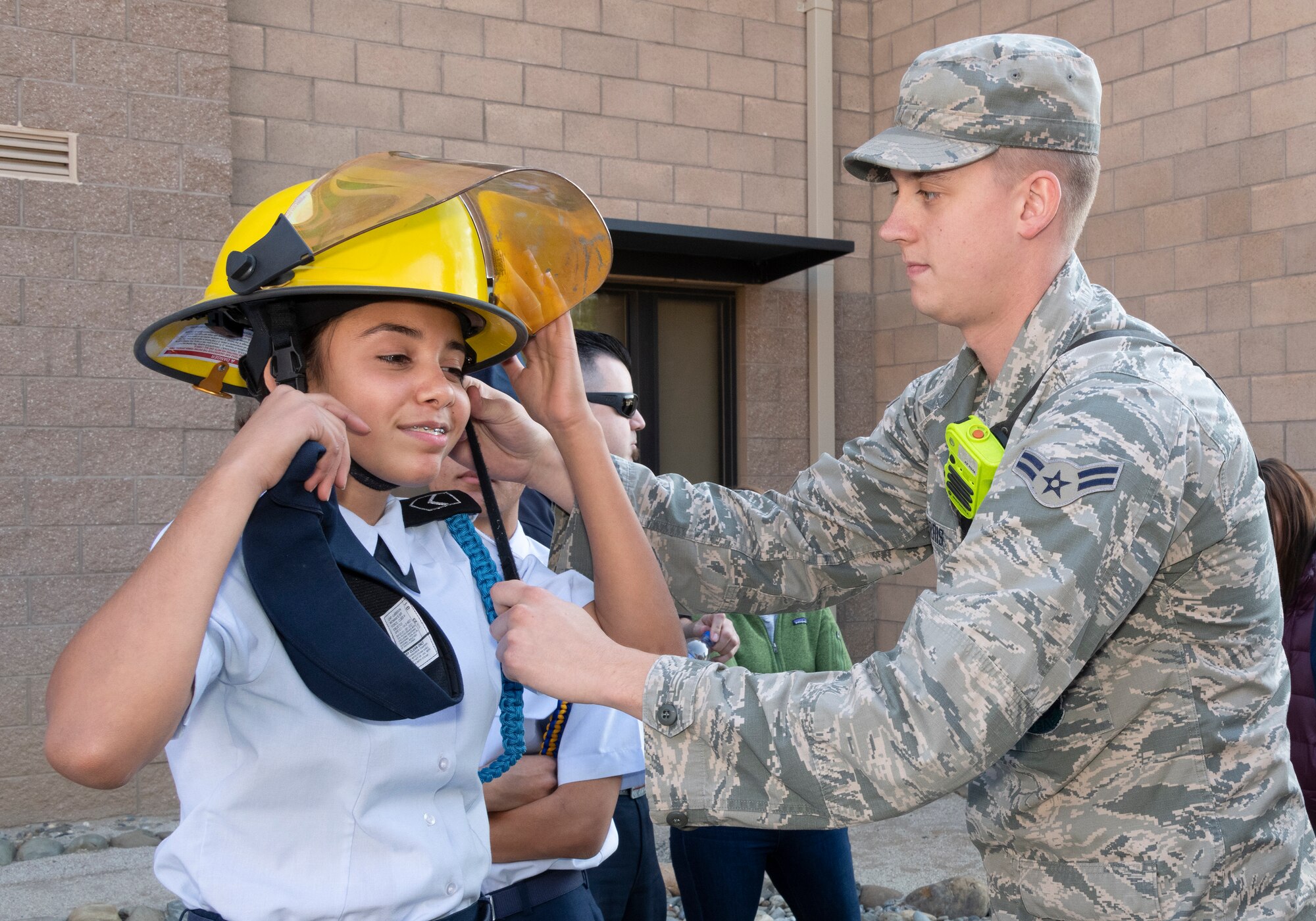 U.S. Air Force Airman 1st Class Cody Ferris, 60th Civil Engineer Squadron firefighter, helps a student try on a helmet during a base tour Nov. 21, 2019, at Travis Air Force Base, California. Travis AFB hosted Junior Reserve Officer Training Corps students from five Northern California high schools and one Oregon high school. The students learned about various U.S. Air Force career fields and toured static aircraft, the Heritage Center museum and dormitories. They also talked with Airmen about military life. (U.S. Air Force photo by Heide Couch)
