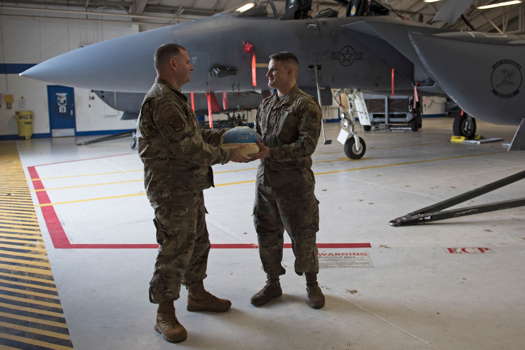 Senior Master Sgt. Michael Holmes, 704th Aircraft Maintenance Squadron first Sergeant, left, delivers a turkey to Senior Airman Franklin Robinson, 704th AMXS crew chief, Nov. 19, 2019, Seymour Johnson Air Force Base, N.C. Airmen from throughout the base were chosen by their leadership to receive a turkey and side dish items for Thanksgiving dinner. (U.S. Air Force photo by Senior Airman Victoria Boyton)