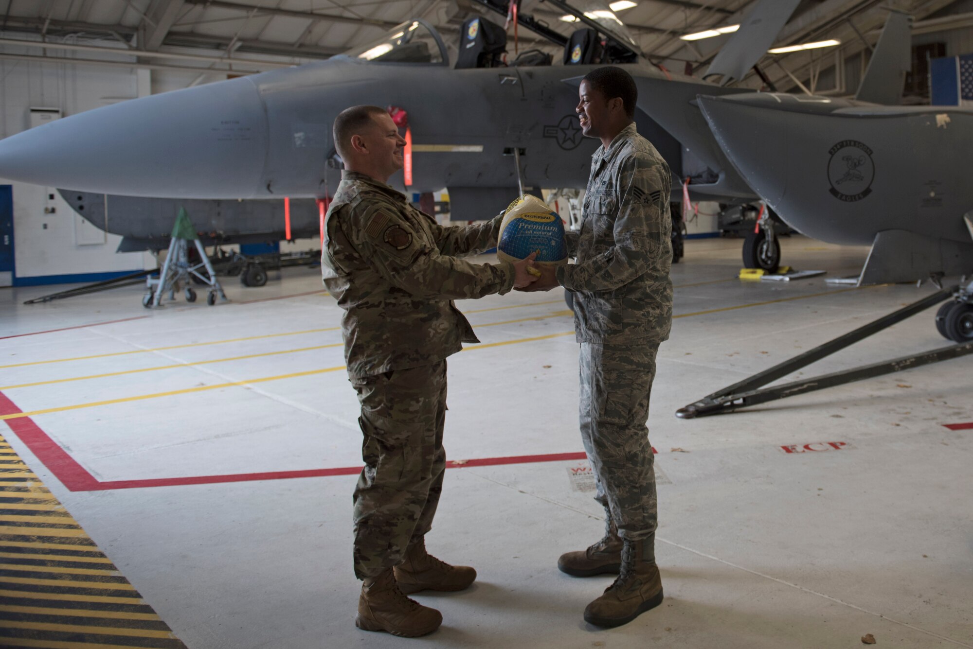 Senior Master Sgt. Michael Holmes, 704th Aircraft Maintenance Squadron first Sergeant, left, delivers a turkey to Senior Airman Germain Magloire, 704th AMXS crew chief, Nov. 19, 2019, Seymour Johnson Air Force Base, N.C. Airmen from throughout the base were chosen by their leadership to receive a turkey and side dish items for Thanksgiving dinner. (U.S. Air Force photo by Senior Airman Victoria Boyton)