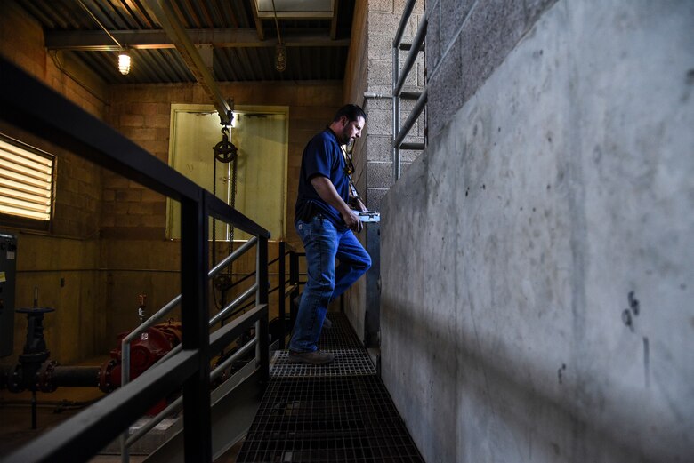 a photo of a repairman inspecting a water well.