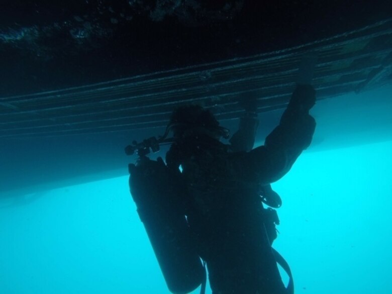 U.S. Marine Corps Cpl. Jack O’Brien, a diver with 3rd Reconnaissance Battalion, 3d Marine Division, removes hard fouling and conducts additional checks on the Keel Cooler Unit of U.S. Army Vessel Harpers Ferry at Naval Station White Beach, Okinawa, Japan, Nov. 15, 2019.