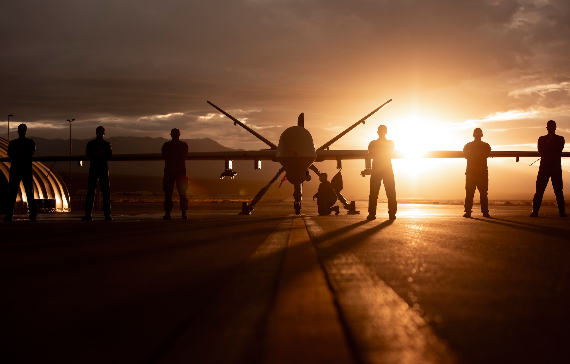 432nd Wing/432nd Air Expeditionary Wing Airmen pose in front of an MQ-9 Reaper underneath a Nevada sunset.