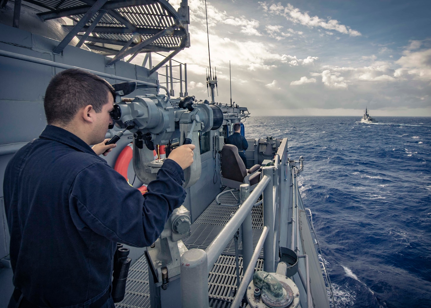 PHILIPPINE SEA (Nov. 21, 2019) Seaman Kevin Henriquez, from New Haven, Conn., looks through binoculars on the bridge of the Ticonderoga-class guided-missile cruiser USS Chancellorsville (CG 62) as the ship maneuvers behind the Royal Australian Navy ship HMAS Hobart (DDG 39) during a group maneuvering exercise with ships from the Royal Australian Navy, Royal Canadian Navy, and Republic of Korea Navy as part of Pacific Vanguard 2019. Chancellorsville is forward-deployed to the U.S. 7th Fleet area of operations in support of security and stability in the Indo-Pacific region.