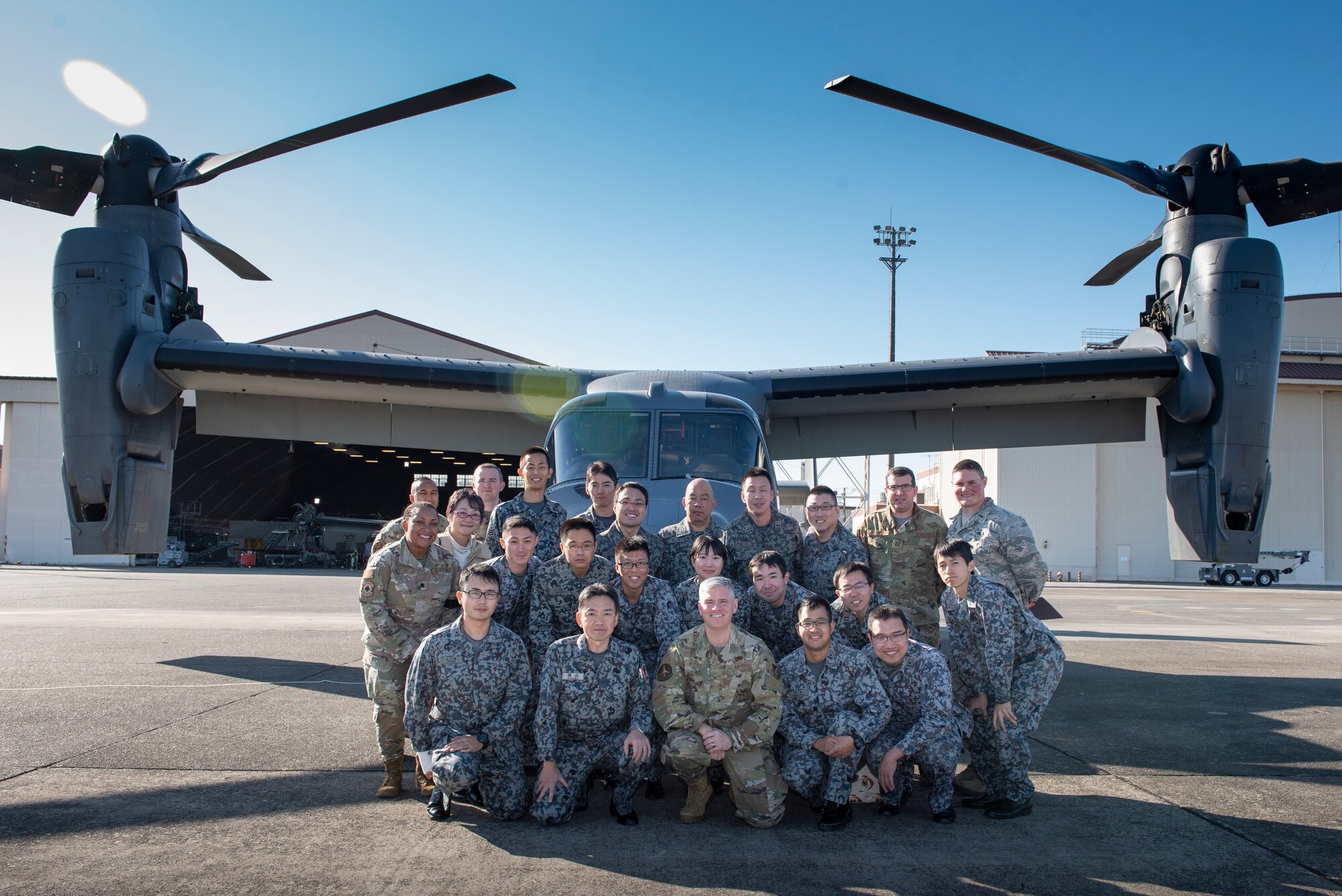 U.S. Air Force and Japanese Air Self-Defense Force members pose for a photo in front of a CV-22 Osprey during a basic maintenance officer tour at Yokota Air Base, Japan, Nov. 21, 2019.